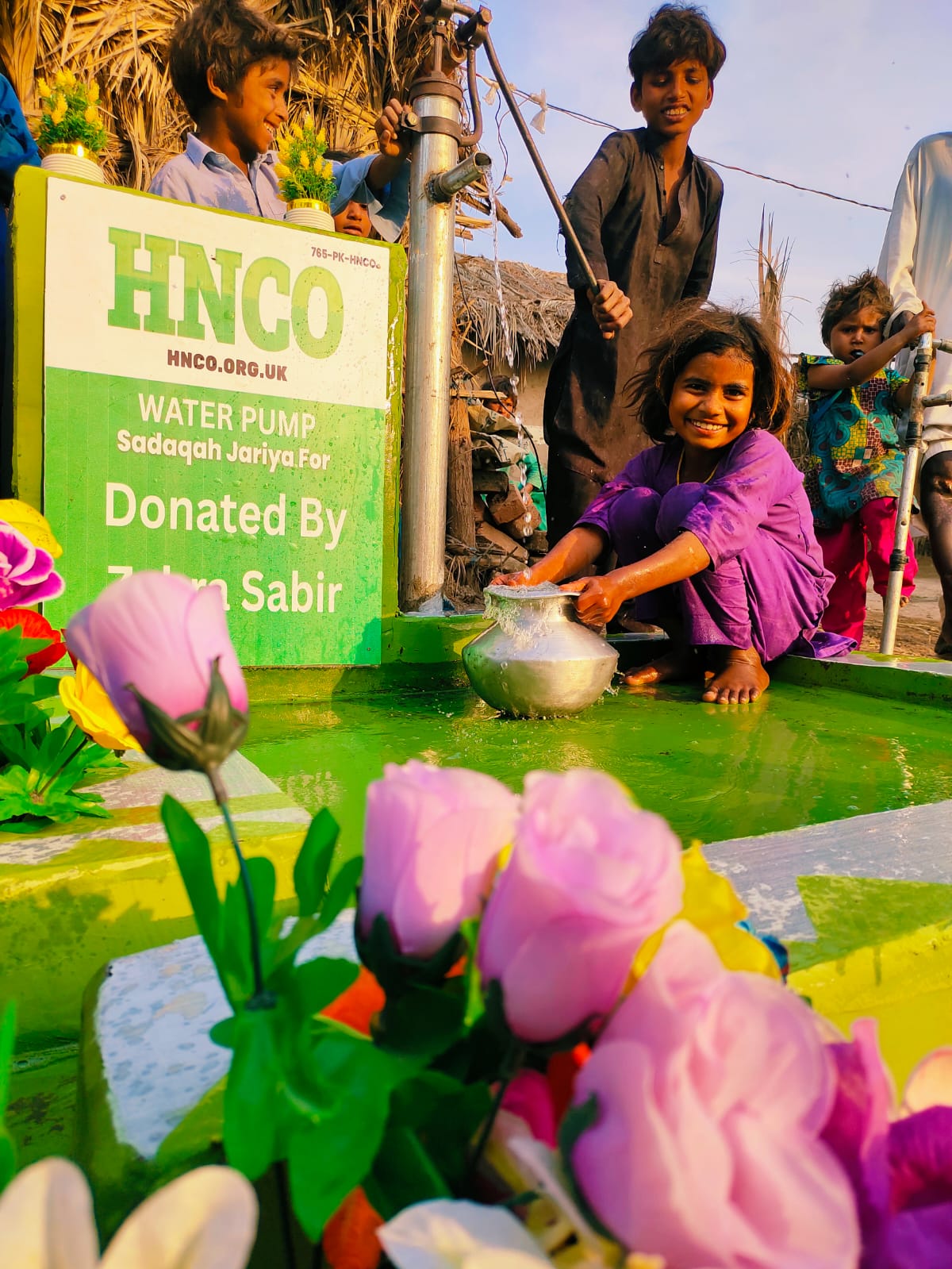 HNCO water pump installed in Pakistan with smiling child collecting fresh water